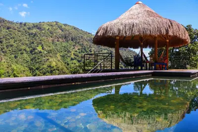 a swimming pool with a straw umbrella and a table and chairs at Finca La Manchuria in Salgar