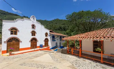 a house with a church and a mountain in the background at Finca La Manchuria in Salgar