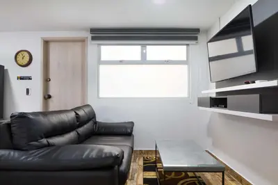 a living room with a black leather couch and a window at Miracle in Medellín