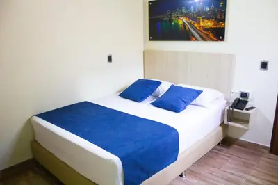 a bedroom with a large bed with blue pillows at Hotel Boutique Street 50 in Medellín