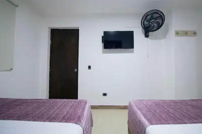 a room with two beds and a clock on the wall at Hotel Boutique Street 50 in Medellín