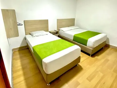 two beds in a small room with green sheets at Hotel Boutique Street 50 in Medellín