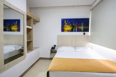 a bedroom with a bed and two paintings on the wall at Hotel Boutique Street 50 in Medellín