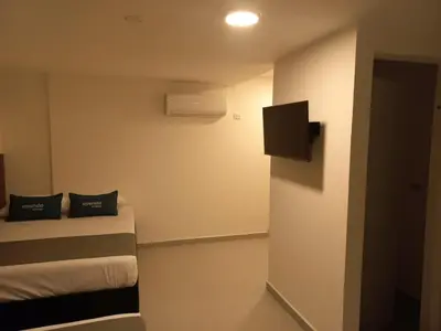a room with two beds and a tv on the wall at Hotel Colombia Avenida in Medellín