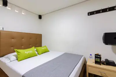 a bedroom with a bed with green pillows and a television at Hotel Colombia Avenida in Medellín