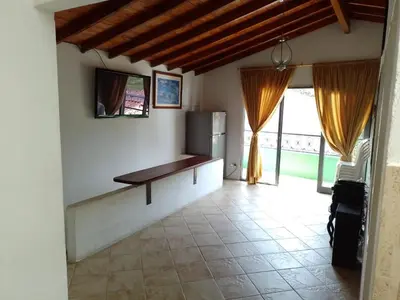 a living room with a table and a tv on the wall at Apartamento de Guatapé in Guatapé