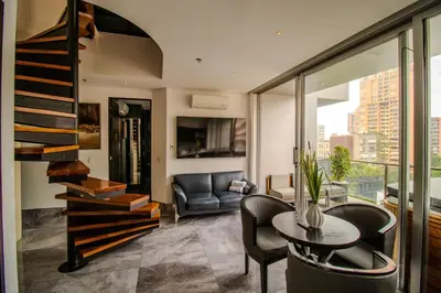 a living room with a staircase and a table and chairs at Haven, A Design Hotel in Medellín