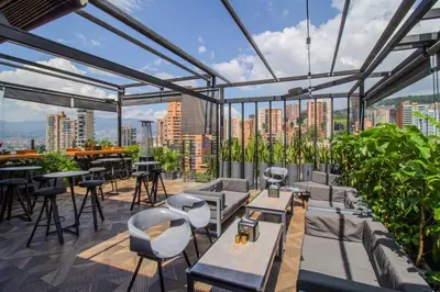 a rooftop patio with tables and chairs and a view of a city at Haven, A Design Hotel in Medellín