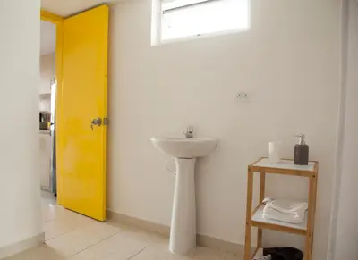 a bathroom with a sink and a yellow door at Apartamento remodelado en el mejor sitio del centro de Medellín Home Aris 401 in Medellín
