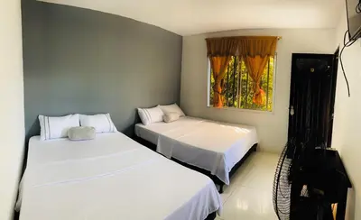 a bedroom with two beds and a television in it at Hotel Los Mangos in San Luis