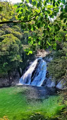 a waterfall in the middle of a river with green water at Hotel Los Mangos in San Luis