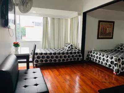 a living room with two beds and a table at Hotel Lleras Premium #1 in Medellín