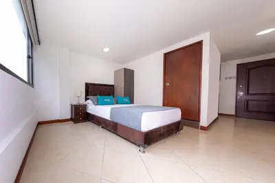 a bedroom with a bed and a wooden door at Hotel Ayenda Palo Alto in Medellín