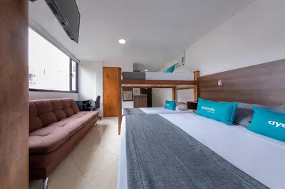 two beds in a room with a couch and a bunk bed at Hotel Ayenda Palo Alto in Medellín
