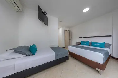 a bedroom with two beds and a tv on the wall at Hotel Ayenda Palo Alto in Medellín