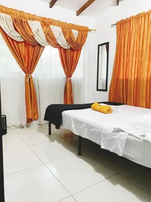 a bedroom with a bed with orange curtains at CAMPO VALDES PARK HOSTEL in Medellín