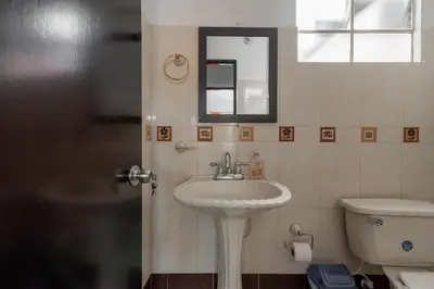 a bathroom with a sink and a toilet and a mirror at CAMPO VALDES PARK HOSTEL in Medellín
