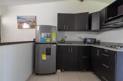 a kitchen with a refrigerator and black cabinets at CAMPO VALDES PARK HOSTEL in Medellín
