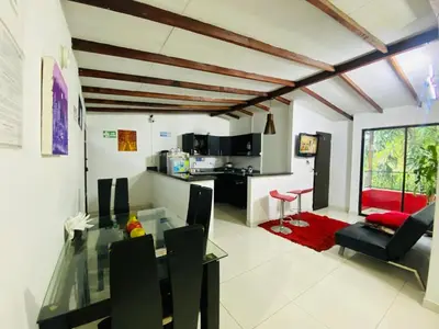 a dining room and living room with a glass table and chairs at CAMPO VALDES PARK HOSTEL in Medellín