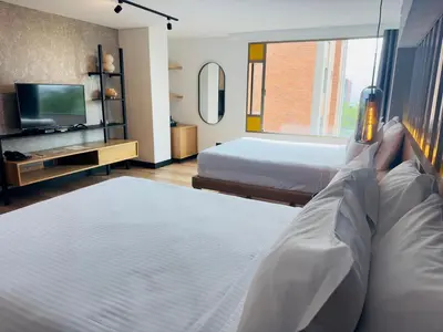 a hotel room with two beds and a television at Hotel Casa Victoria in Medellín