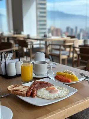 a table with a breakfast of eggs bacon and toast at Hotel Casa Victoria in Medellín