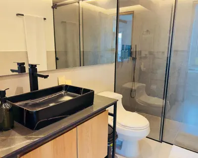 a bathroom with a black sink and a toilet at Hotel Casa Victoria in Medellín