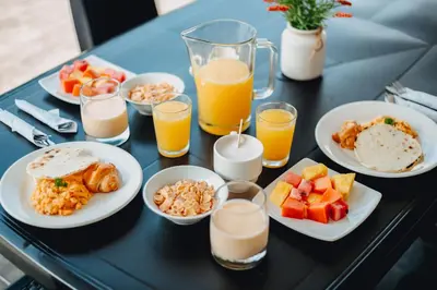 a table with plates of food and glasses of orange juice at Tik by Bernalo Hotels in Medellín