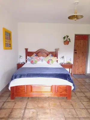 a bedroom with a large bed with a wooden headboard at Alojamiento Rural Jardín Consentido in Jardin