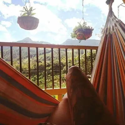 a person laying in a hammock looking out a window at Alojamiento Rural Jardín Consentido in Jardin