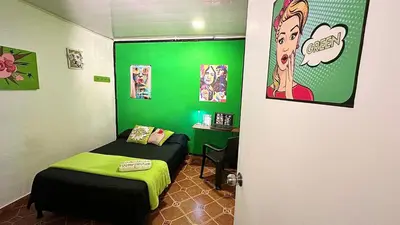 a green room with a bed and a desk at Casa Egos Pop Laureles in Medellín