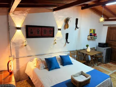 a bedroom with a bed with blue pillows and a table at Compostela cabaña privada (private cabin for rent) in Jardin