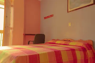 a bedroom with a bed with a colorful blanket at Hotel Felicina in Jericó