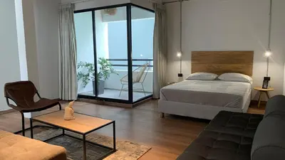 a bedroom with a bed and a living room at Soy Local Primavera in Medellín