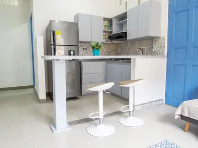 a kitchen with a counter with two stools and a refrigerator at Hotel Azulado Jericó in Jericó