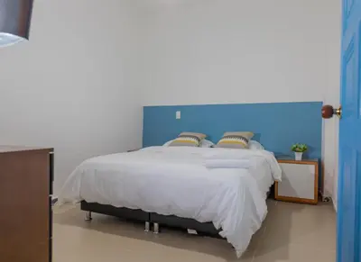 a bedroom with a large bed with a blue headboard at Hotel Azulado Jericó in Jericó