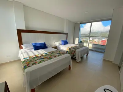 a bedroom with two beds and a large window at Hotel Santorini in Guatapé