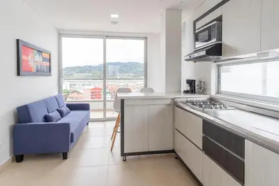 a kitchen with a couch and a stove top oven at Hotel Santorini in Guatapé