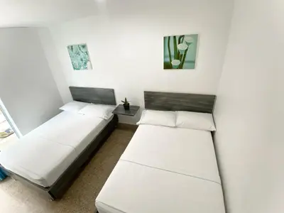 two beds in a room with white walls at Hotel Plaza Mayor Itagui in Itagüí