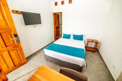 a bedroom with a bed with blue pillows and a tv at Hotel Santa Laura in Jericó