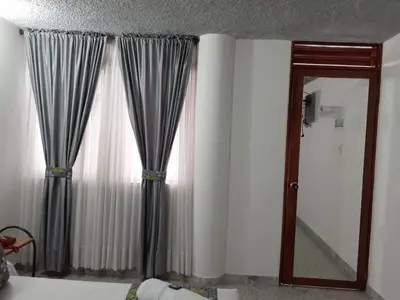 a bedroom with curtains and a mirror and a bed at Hotel Mirador Santana in Anserma