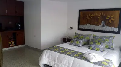 a bedroom with a white bed with blue and yellow pillows at Hotel Mirador Santana in Anserma