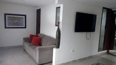 a living room with a couch and a flat screen tv at Hotel Mirador Santana in Anserma