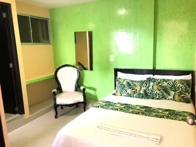 a green bedroom with a bed and a chair at Hotel Ecosuite Quibdó in Quibdó