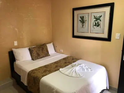 a hotel room with two beds and a picture on the wall at Hotel Ecosuite Quibdó in Quibdó