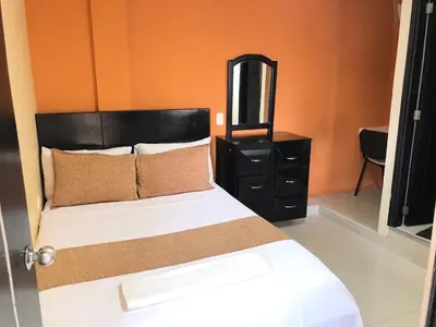a bedroom with a bed with a black dresser and a mirror at Hotel Ecosuite Quibdó in Quibdó