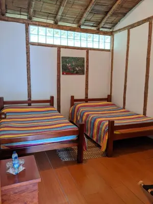 two beds in a room with two windows at Hacienda Guayabal in Chinchiná