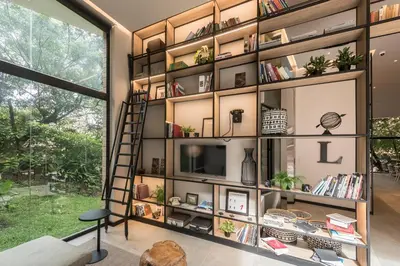 a book shelf in a living room with a television at Lettera Hotel in Medellín