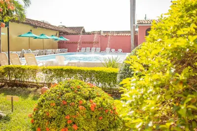a garden with a swimming pool with chairs and umbrellas at Casa Hotel Guaracú in Santa Fe de Antioquia