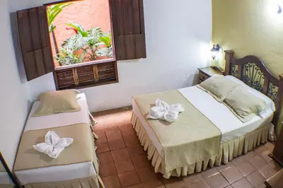 a hotel room with two beds and a window at Casa Hotel Guaracú in Santa Fe de Antioquia