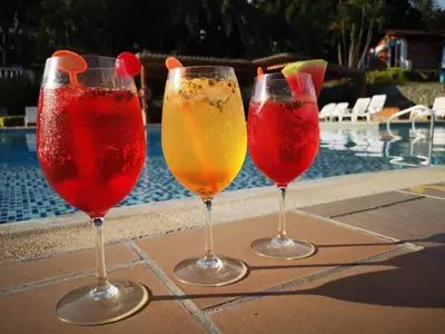 three wine glasses sitting on a table near a swimming pool at Hosteria Guaracú in San Jerónimo